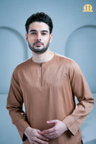 Man wearing a brown long-sleeve shirt against a light blue background